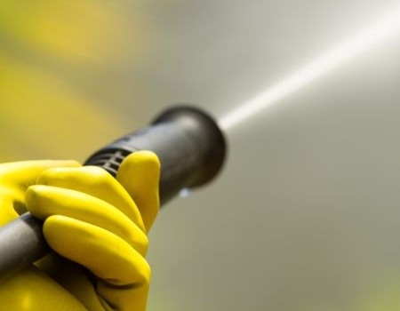 Technician pressure washing in Hudson, MA after winter